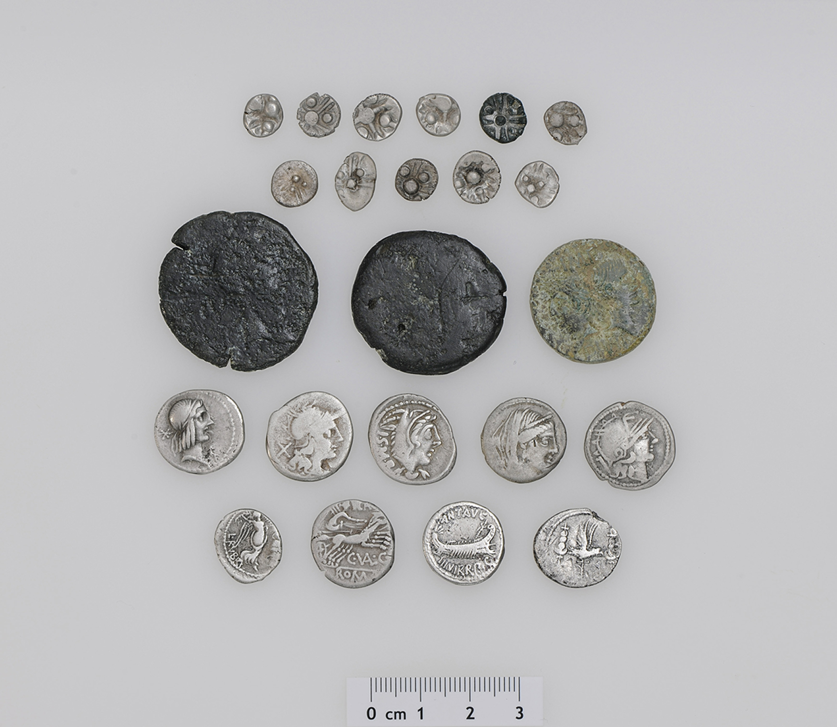 Die 23 Silber- und Bronzemünzen aus keltischer und römischer Zeit sind über 2000 Jahre alt. Es ist erst der zweite Mischfund von keltischen und römisch-republikanischen Silbermünzen in der Schweiz. Zu den 11 norischen Silbermünzen (Reihe 1 und 2 auf dem Foto) gibt es schweizweit keine Vergleichsfunde. Der Fund umfasst weiter 8 römische Silber- und 3 Bronzemünzen sowie die Imitation einer römischen Silbermünze, vermutlich aus dem südosteuropäischen Raum (Reihe 3 bis 5 auf dem Foto). Die römischen Silber-Denare und der Quinar (Reihe 4 und 5 auf dem Foto) weisen die Namen der Münzmeister C. Valerius Flaccus, L. Thorius Balbus, L. Piso Frugi und L. Rubrius Dossenus sowie den Namen des Feldherrn Marcus Antonius auf. Das jüngste Fundstück wurde um 15–9/7 v. Chr. in Nemausus, dem heutigen Nîmes (Frankreich), geprägt und gibt einen Hinweis darauf, ab wann der Schatzfund in den Boden gelangt ist. Foto: Res Eichenberger (Amt für Denkmalpflege und Archäologie des Kantons Zug).
